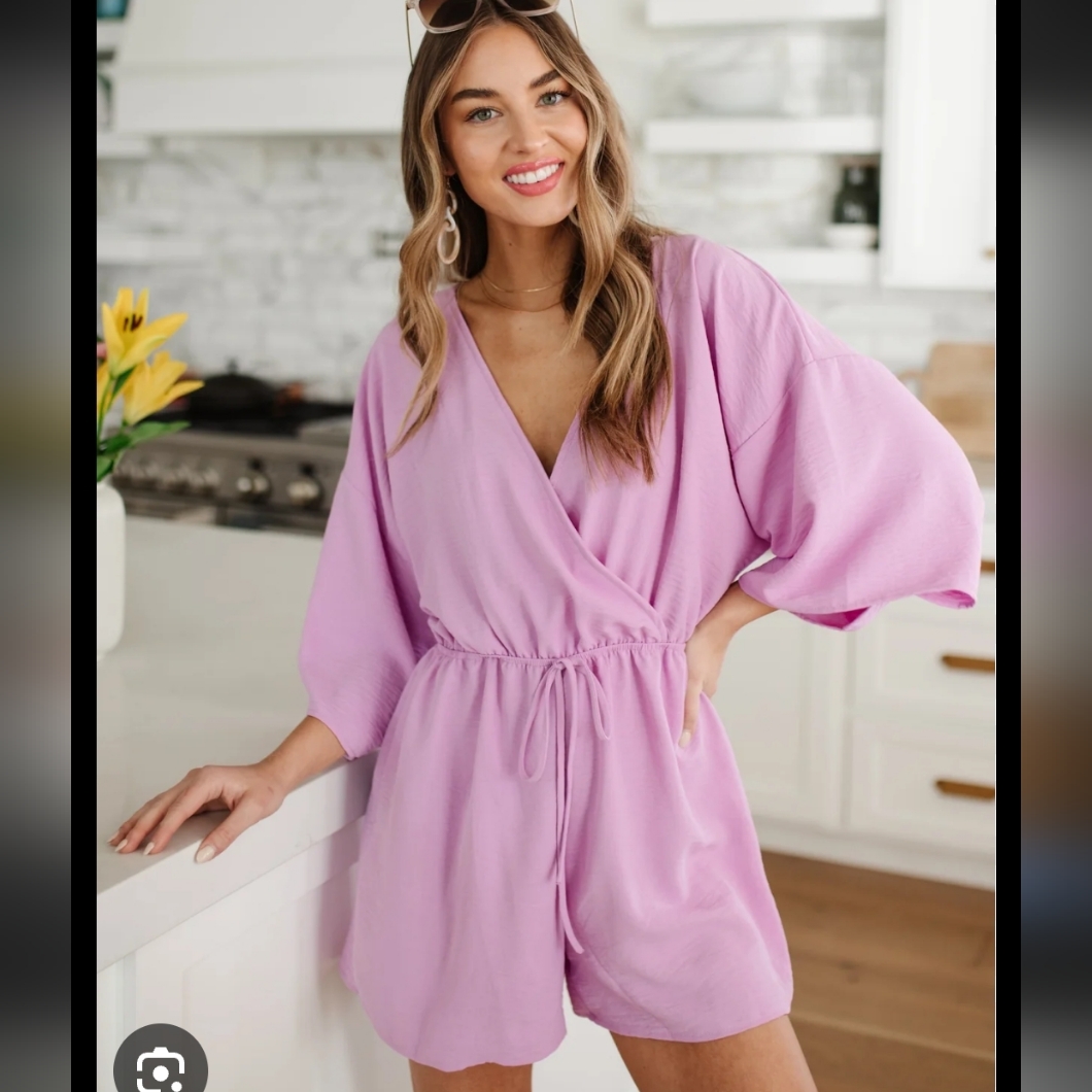Lavender Romper Features A Faux Wrap Front, Tie Waist, And Flutter Sleeves